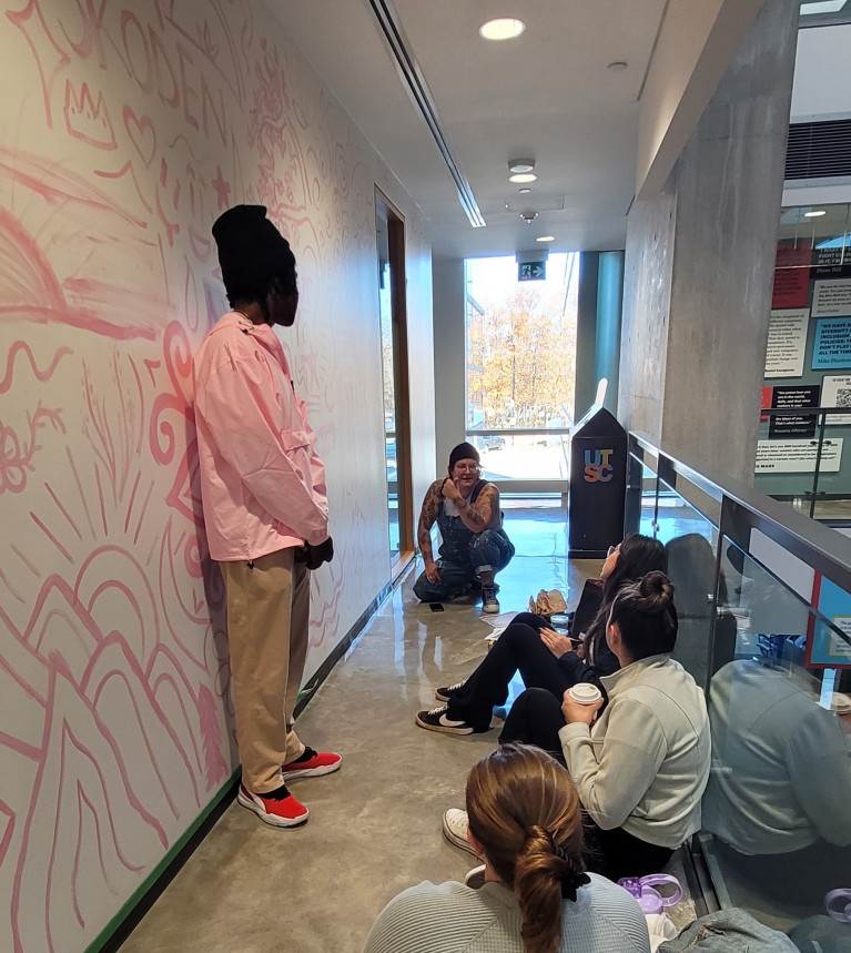 Students having a workshop with an Indigenous artist in the hallway of the Kina Wiiya Enadong Building
